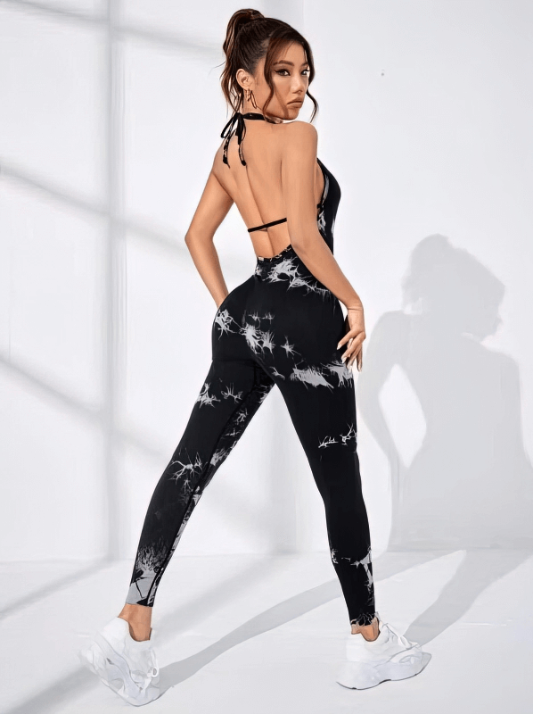 Woman wearing a fashionable elastic sports jumpsuit, open back style ideal for yoga, in a breathable nylon print design.